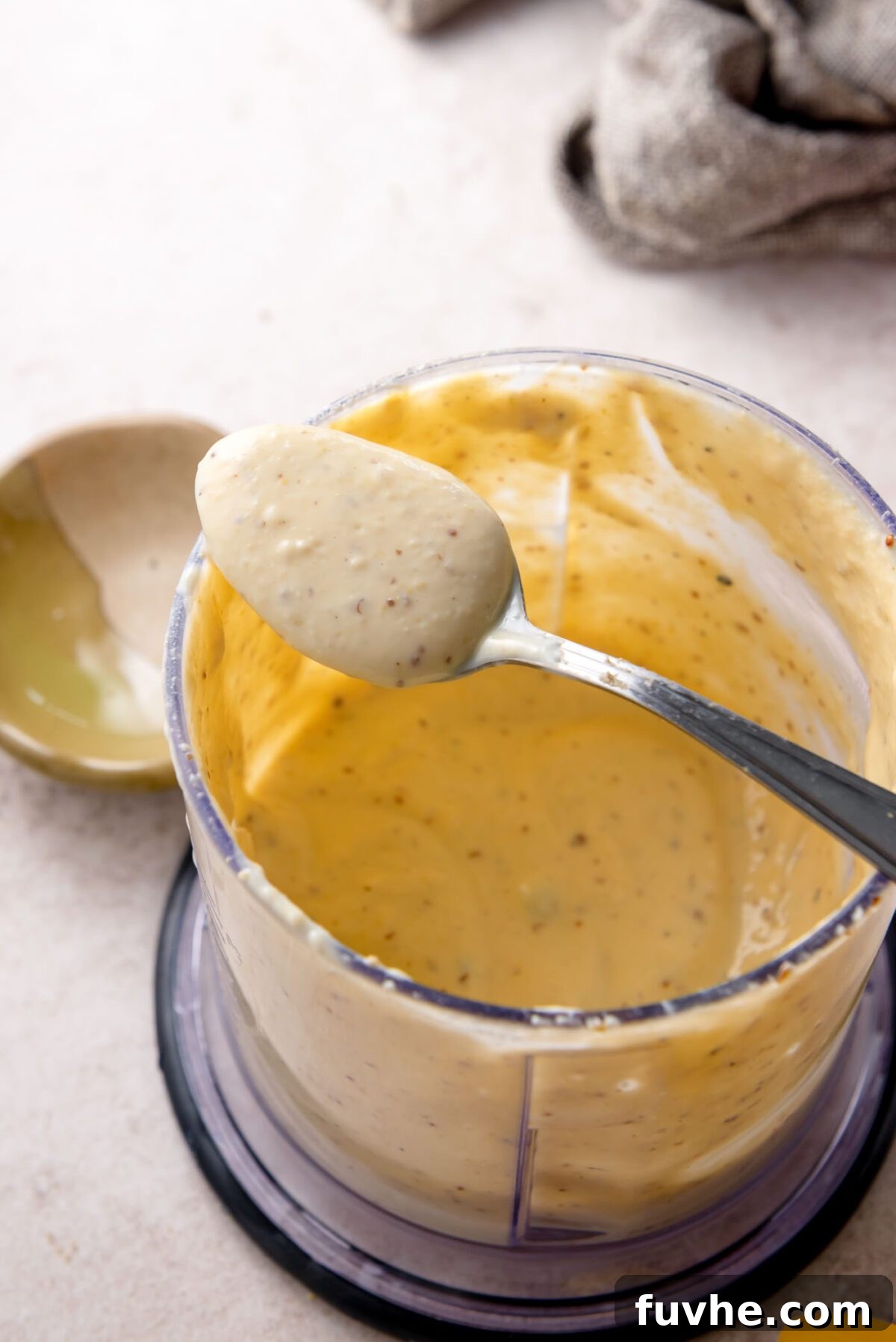 Golden Roasted Vegetable Caesar 7 Creamy vegan Caesar dressing blended smooth in a small food processor, shown on a spoon, illustrating its perfect consistency.