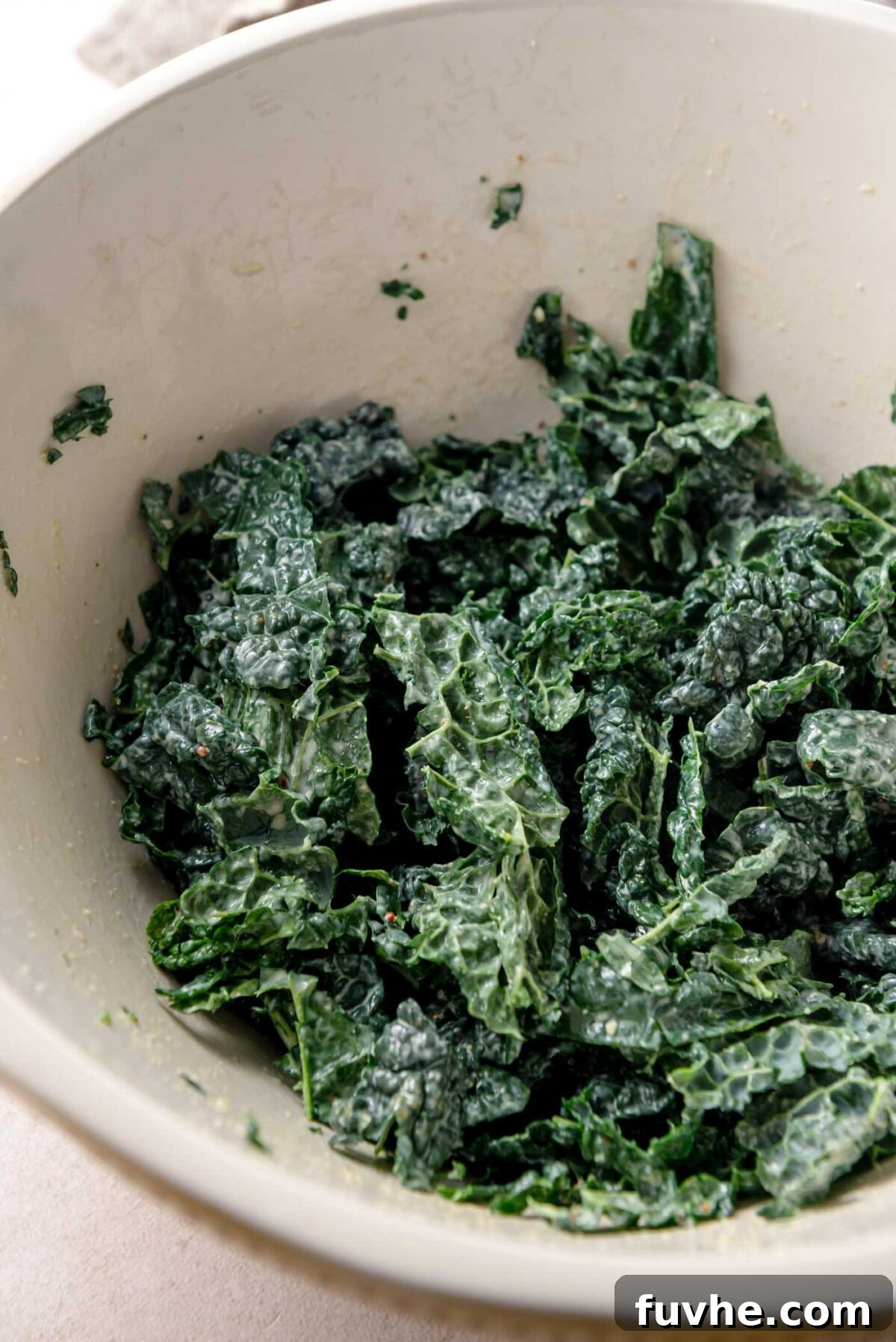 Golden Roasted Vegetable Caesar 8 Chopped kale leaves massaged with dressing in a mixing bowl, showing softened texture and glossy coating.
