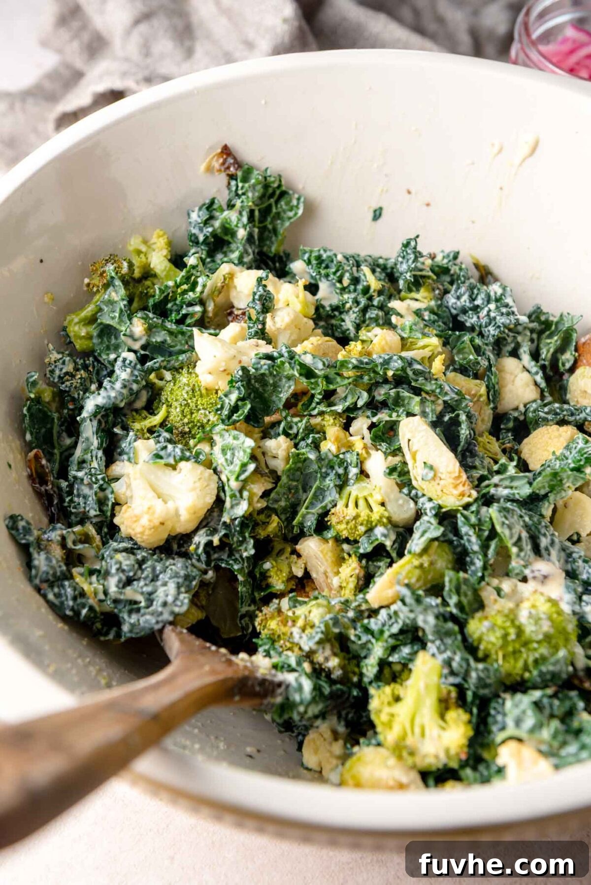 Golden Roasted Vegetable Caesar 9 Large mixing bowl of kale Caesar salad with roasted broccoli and cauliflower tossed in creamy dressing, ready for serving.