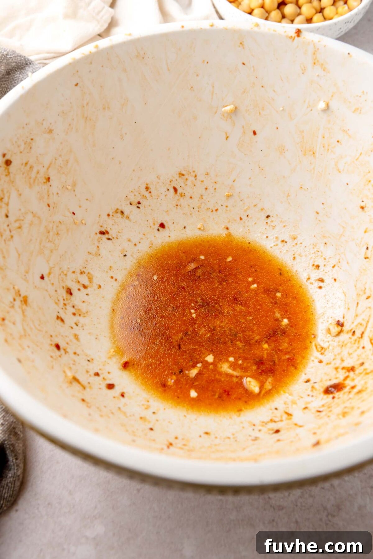 Lemon harissa dressing ingredients being whisked together in a mixing bowl.