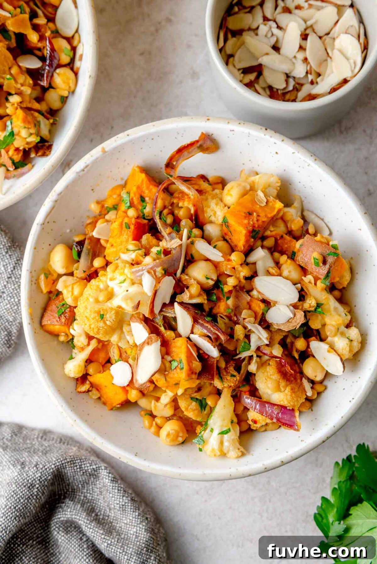 The final Harissa Roasted Vegetable Lentil Salad in a serving bowl, garnished with toasted sliced almonds.